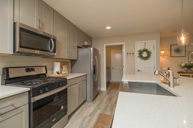 kitchen featuring sink, hanging light fixtures, light wood-type flooring, gray cabinets, and stainless steel appliances