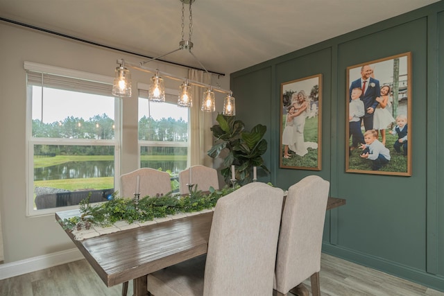 dining area with light wood-type flooring and a water view