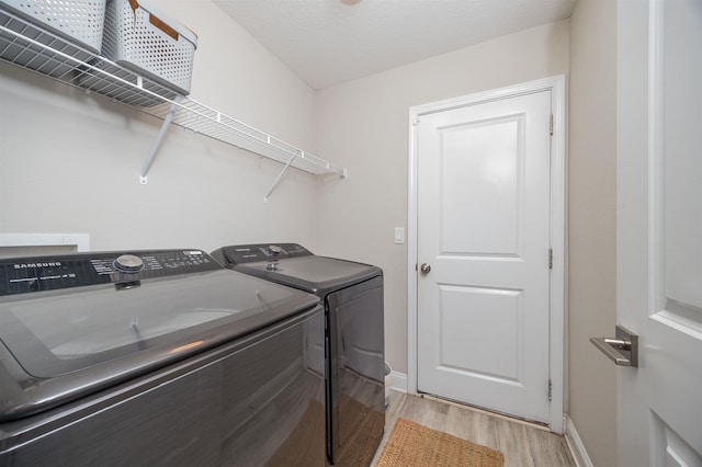 laundry area with independent washer and dryer and light wood-type flooring