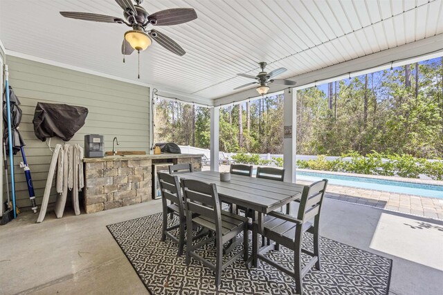 view of patio / terrace featuring ceiling fan, exterior bar, an outdoor pool, an outdoor kitchen, and outdoor dining space