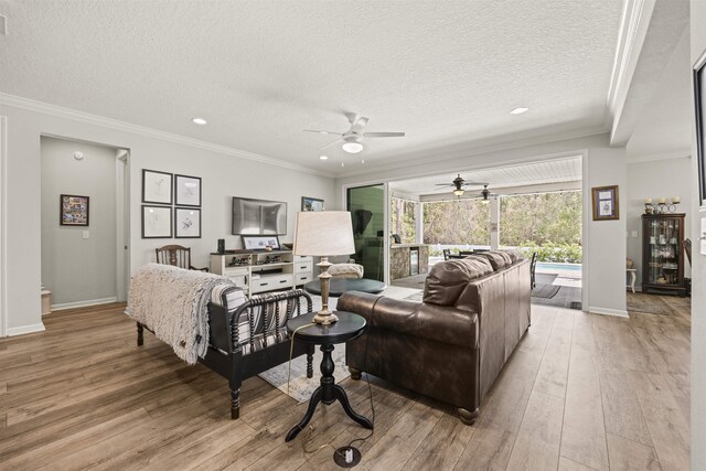living room with light wood-type flooring, a ceiling fan, and ornamental molding