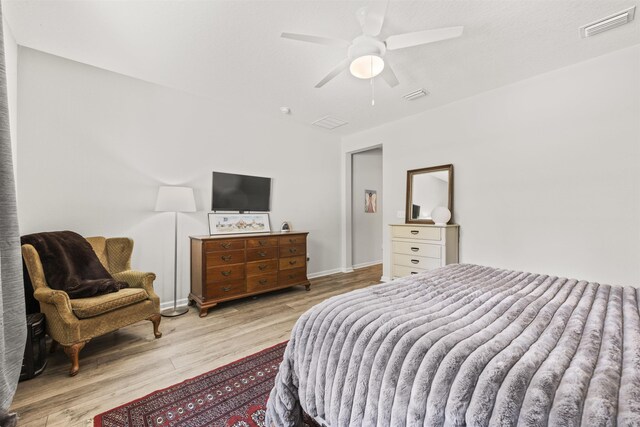 bedroom featuring baseboards, ceiling fan, visible vents, and wood finished floors