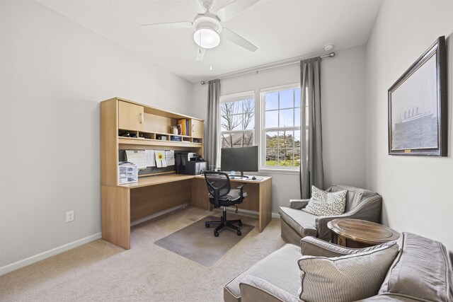 carpeted office with baseboards and a ceiling fan