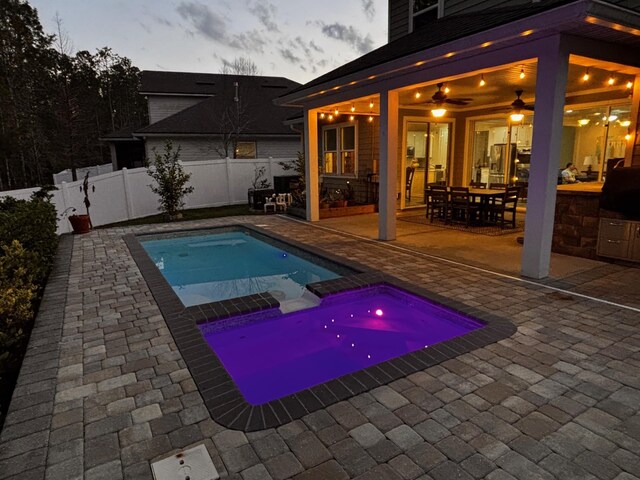 view of pool featuring a patio, a fenced backyard, a pool with connected hot tub, and outdoor dining space