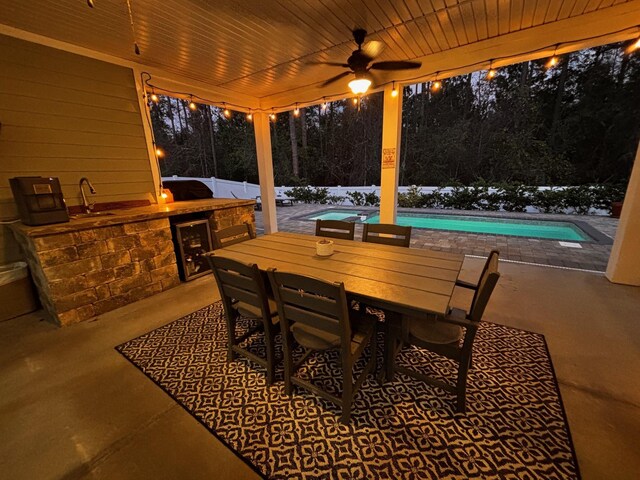 view of patio with a sink, outdoor dining area, an outdoor pool, an outdoor kitchen, and a ceiling fan