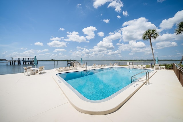 view of pool featuring a water view and a patio