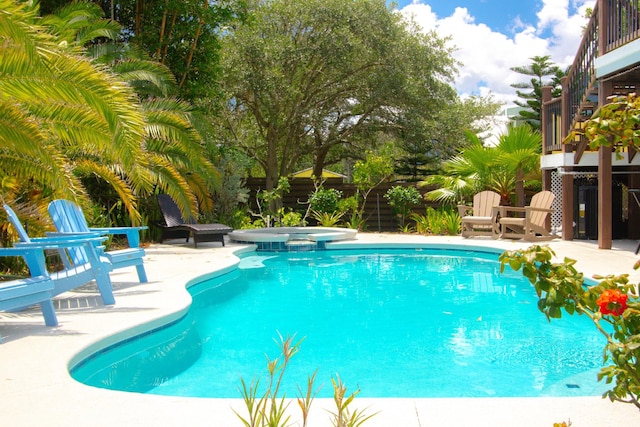 view of pool with a patio area, fence, and a pool with connected hot tub