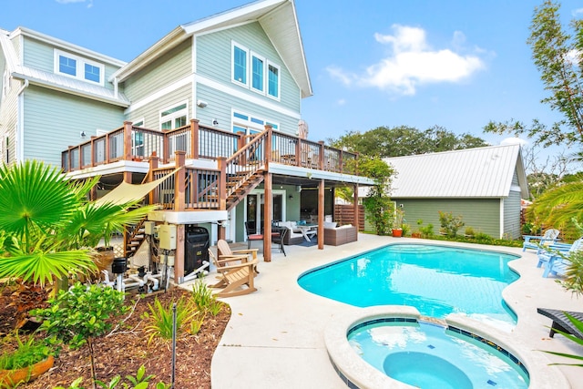 back of house featuring stairs, a patio area, a pool with connected hot tub, and a wooden deck