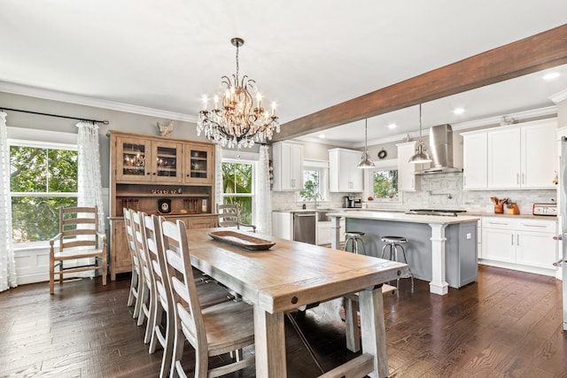 dining area featuring sink, a notable chandelier, beamed ceiling, crown molding, and dark wood-type flooring