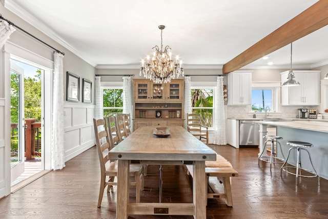 dining area featuring a chandelier, dark wood-type flooring, ornamental molding, and sink