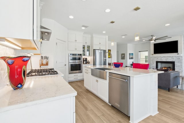 kitchen with hanging light fixtures, white cabinets, light wood finished floors, and stainless steel appliances