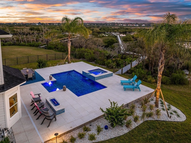 view of pool featuring a patio, a fenced backyard, a lawn, and a pool with connected hot tub