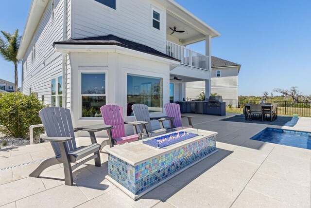 view of patio with a balcony, fence, ceiling fan, a fire pit, and grilling area