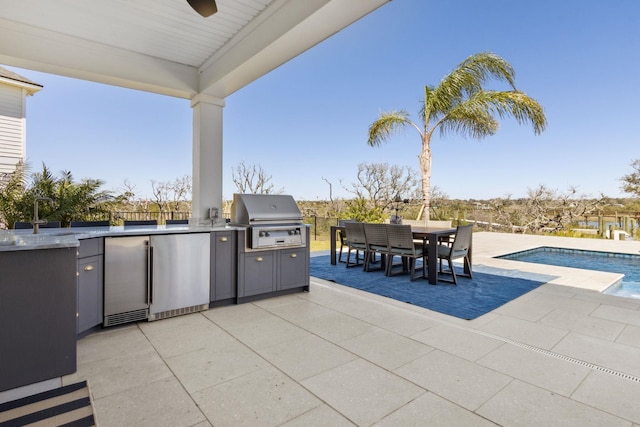 view of patio / terrace with grilling area, outdoor dining space, an outdoor kitchen, an outdoor pool, and a sink