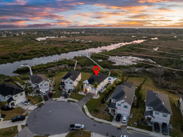 aerial view at dusk with a water view and a residential view