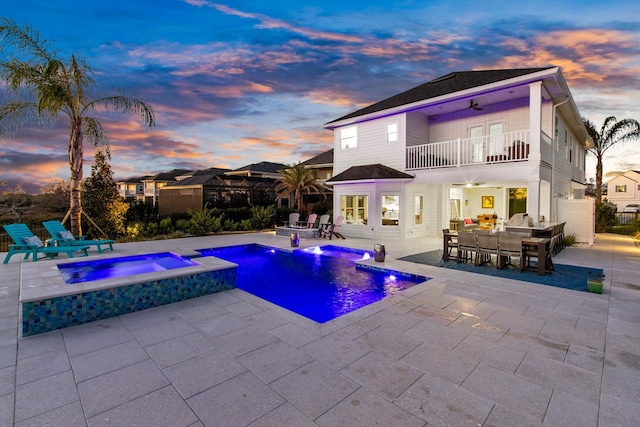 pool at dusk with a patio area, outdoor dining space, and ceiling fan