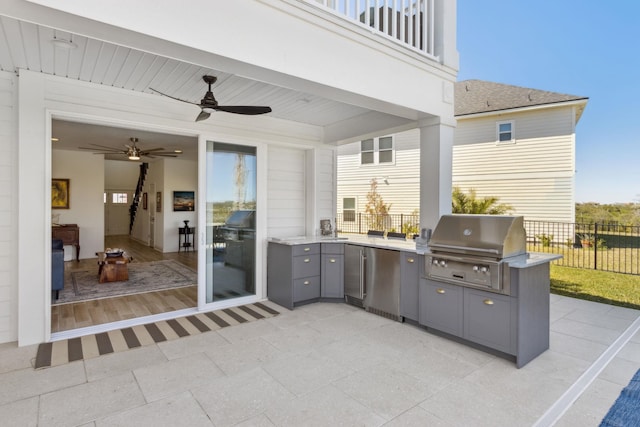 view of patio featuring ceiling fan, fence, exterior kitchen, a balcony, and area for grilling