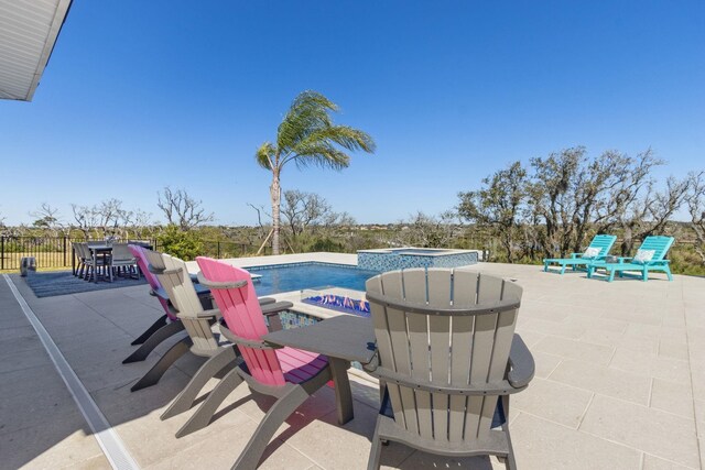 view of patio / terrace featuring outdoor dining space, an in ground hot tub, fence, and an outdoor pool