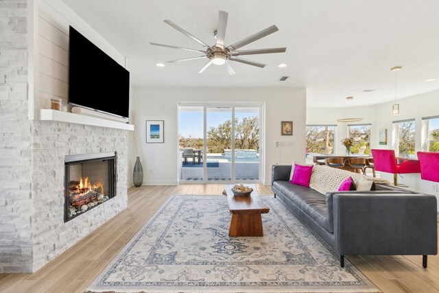 living room featuring a fireplace, wood finished floors, and a healthy amount of sunlight