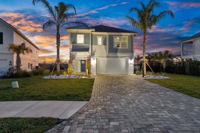 view of front of house featuring decorative driveway, a front lawn, an attached garage, and fence