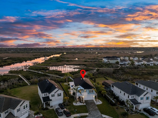 aerial view at dusk featuring a water view and a residential view