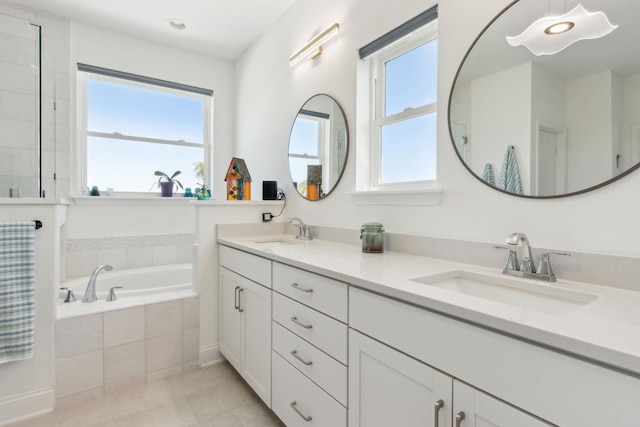 bathroom featuring tile patterned flooring, a garden tub, double vanity, and a sink