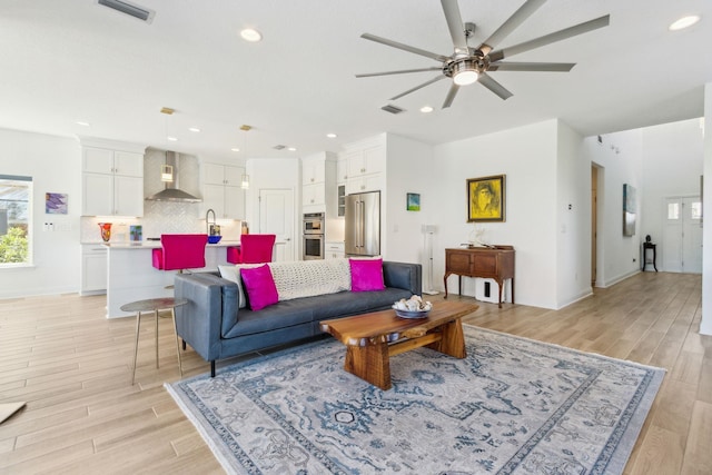 living room with recessed lighting, visible vents, a ceiling fan, and light wood finished floors