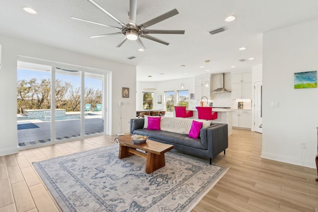 living room with visible vents, baseboards, recessed lighting, ceiling fan, and light wood-style floors