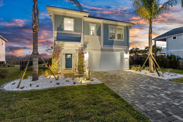 view of front of house with decorative driveway, fence, a garage, and a lawn