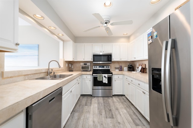 kitchen featuring backsplash, white cabinets, sink, light hardwood / wood-style flooring, and stainless steel appliances