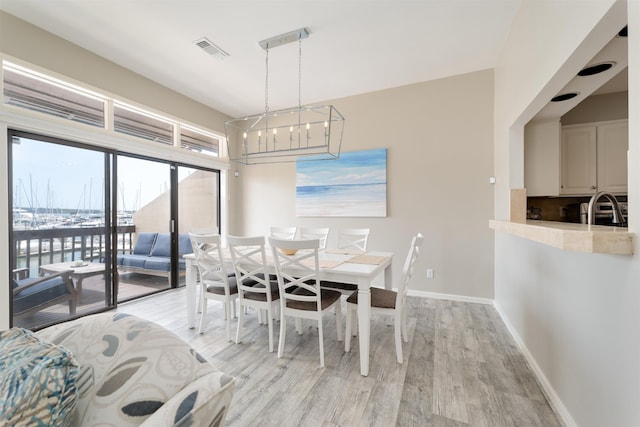 dining room with sink, light hardwood / wood-style flooring, and an inviting chandelier