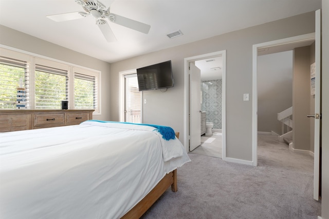 carpeted bedroom with ensuite bathroom and ceiling fan