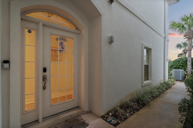 exterior entry at dusk featuring central AC unit