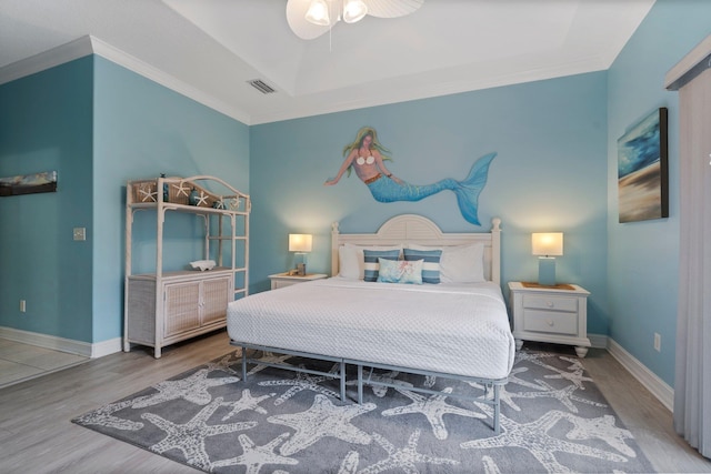 bedroom featuring ceiling fan, wood-type flooring, a tray ceiling, and crown molding