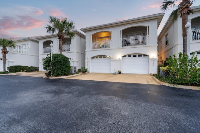 view of front of house with a balcony, a garage, and central air condition unit