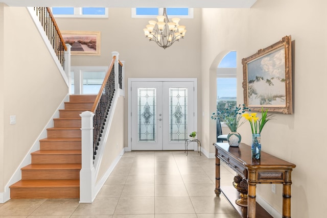 entryway with an inviting chandelier, a towering ceiling, french doors, and light tile patterned floors