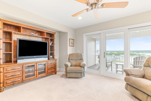 living room with light colored carpet, ceiling fan, and a water view