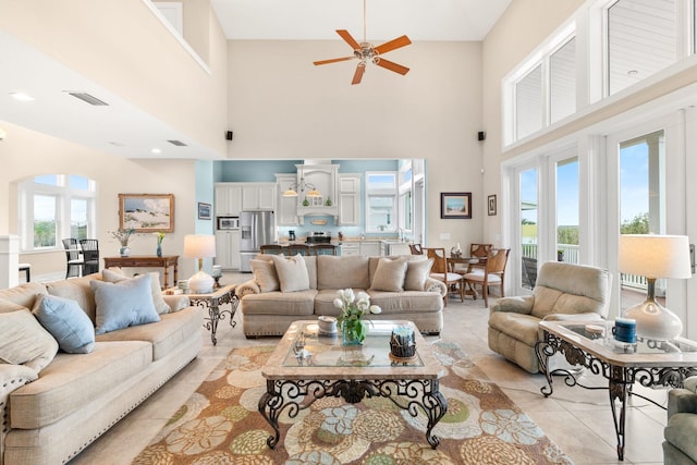 tiled living room featuring ceiling fan and a towering ceiling