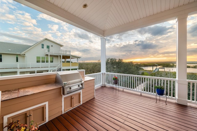 deck at dusk featuring area for grilling, grilling area, and a water view