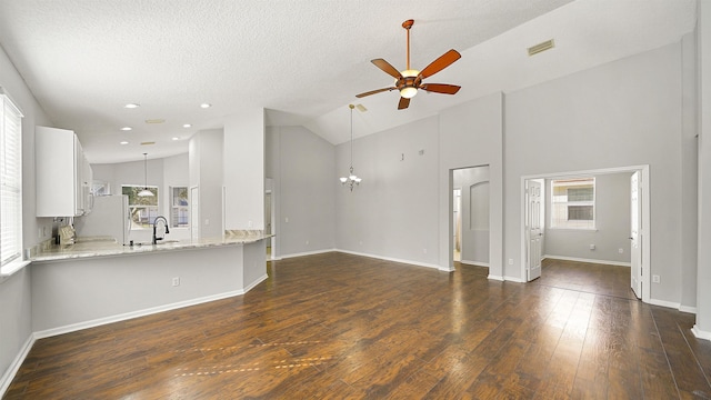 unfurnished living room featuring sink, a textured ceiling, ceiling fan with notable chandelier, dark wood-type flooring, and high vaulted ceiling