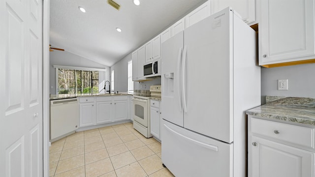 kitchen with white appliances, light tile patterned flooring, vaulted ceiling, sink, and white cabinetry