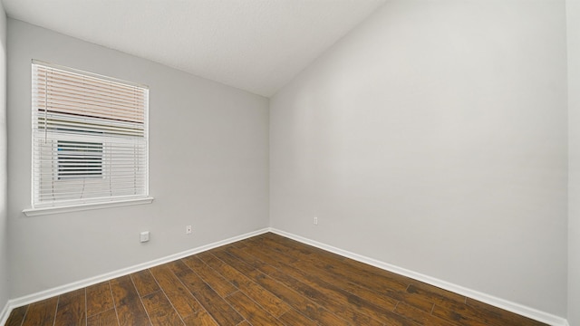 empty room with dark wood-type flooring and lofted ceiling