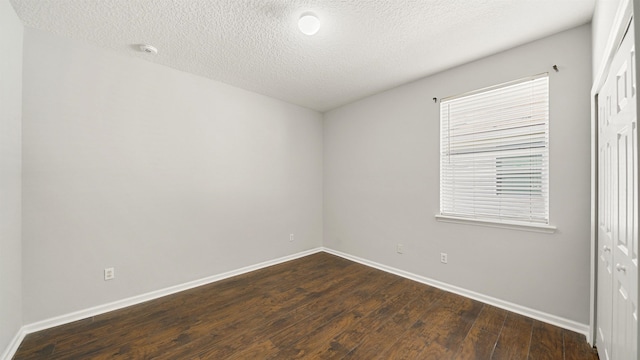 unfurnished room with dark hardwood / wood-style flooring and a textured ceiling