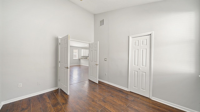 empty room featuring dark wood-type flooring and high vaulted ceiling