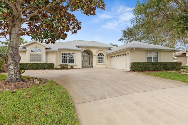 view of front of property with an attached garage, driveway, a shingled roof, and stucco siding