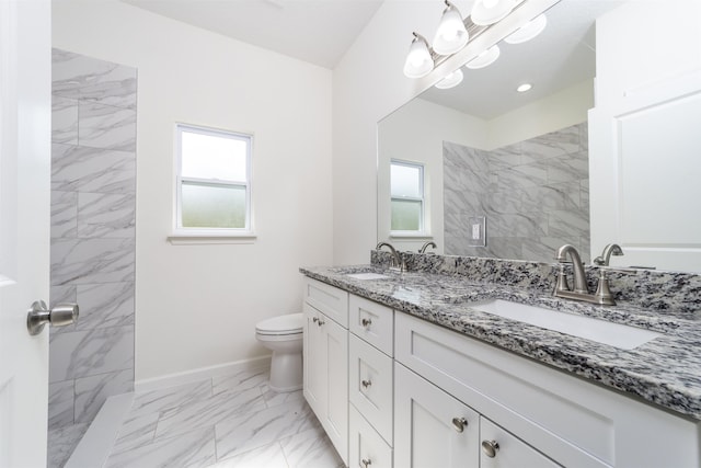 bathroom with a tile shower, vanity, and toilet