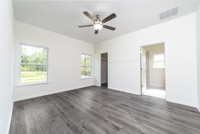 unfurnished bedroom featuring multiple windows, ceiling fan, dark hardwood / wood-style flooring, and ensuite bath