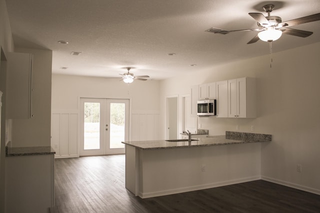 4350 Theresa St, Hastings, FL 32145 - kitchen with stainless steel microwave, a ceiling fan, a peninsula, dark stone counters, and dark wood-style floors