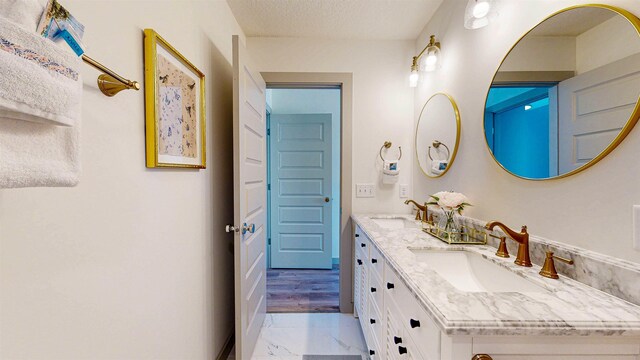 16/18/20 Inlet Pl, Saint Augustine, FL 32080 - bathroom featuring marble finish floors, double vanity, baseboards, and a textured ceiling