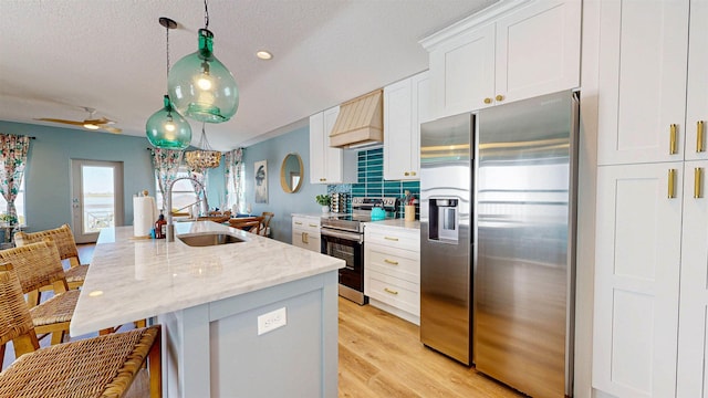 16/18/20 Inlet Pl, Saint Augustine, FL 32080 - kitchen featuring appliances with stainless steel finishes, a sink, premium range hood, white cabinetry, and a textured ceiling